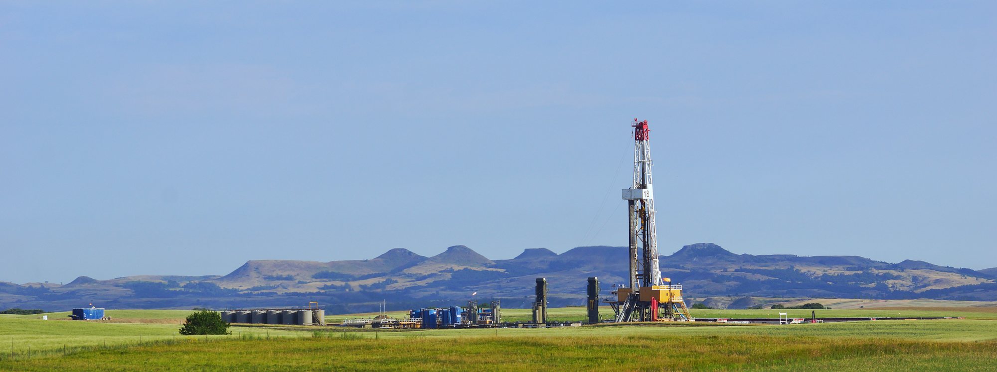 Drilling rig on the prairie with buttes on the horizon