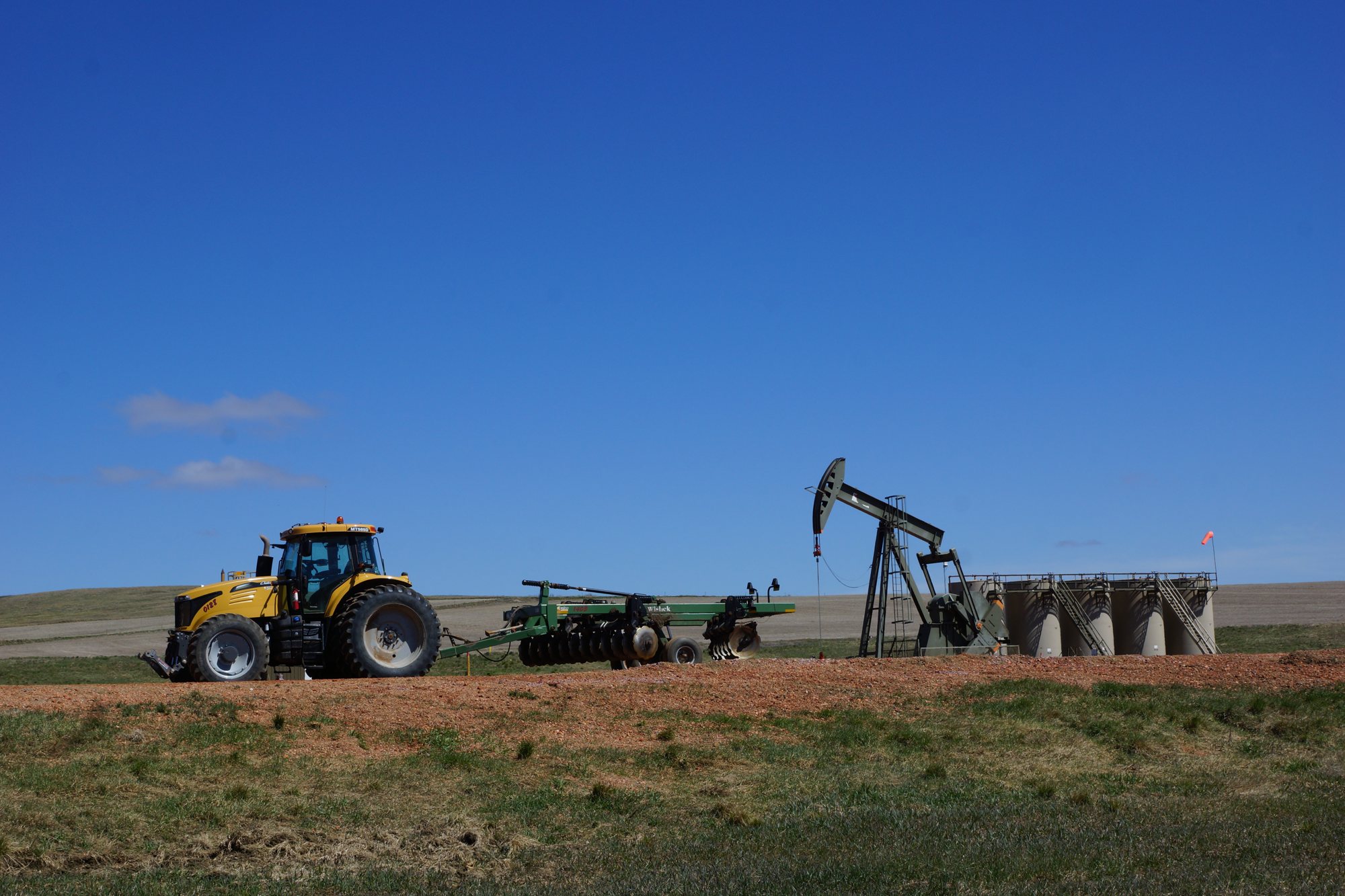 Tractor working a field beside a pumpjack